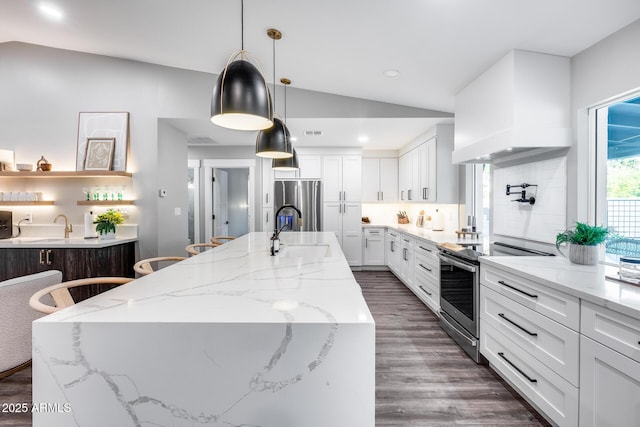 kitchen with a center island with sink, custom range hood, a sink, lofted ceiling, and stainless steel appliances