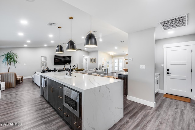 kitchen with appliances with stainless steel finishes, a sink, baseboards, open floor plan, and visible vents