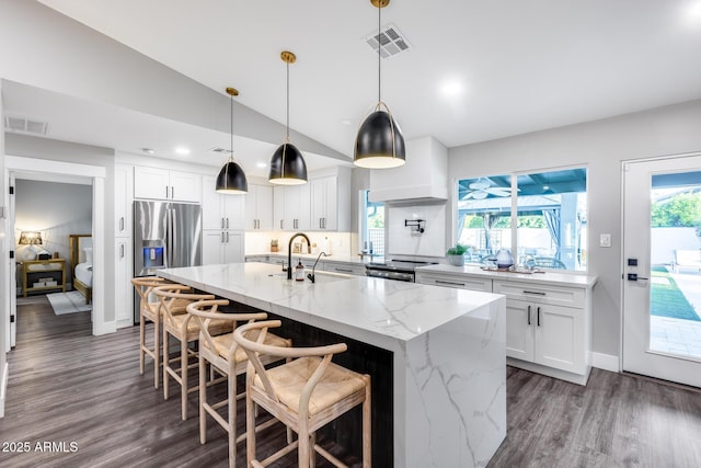 kitchen with dark wood-style flooring, visible vents, a sink, stainless steel fridge, and white cabinetry