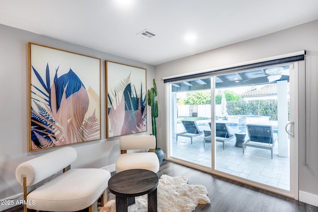 living area with visible vents, baseboards, and wood finished floors