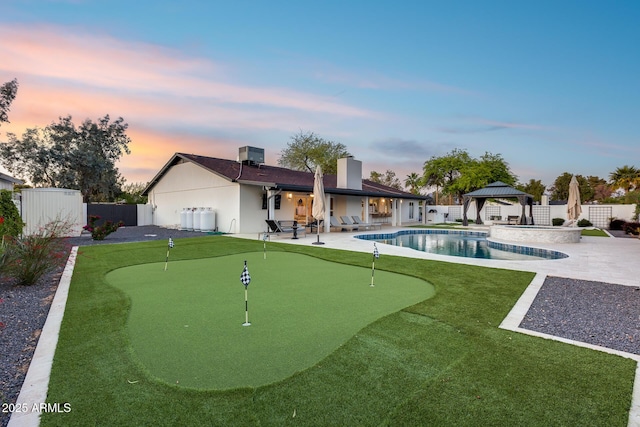 rear view of property featuring a gazebo, a fenced backyard, a fenced in pool, a patio area, and an outdoor structure