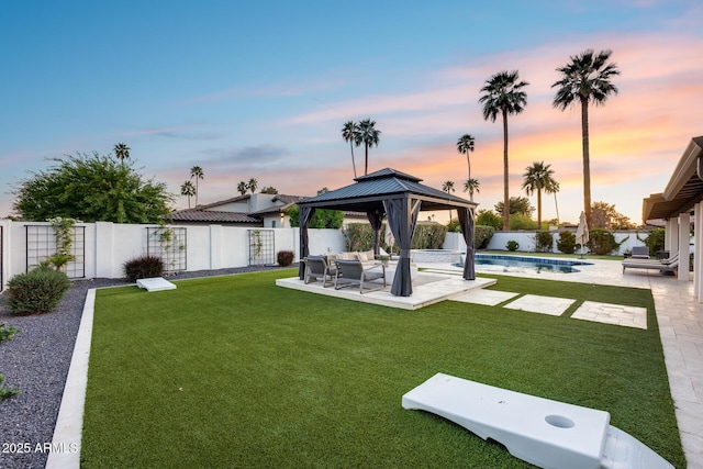 yard at dusk featuring a patio, a gazebo, and a fenced backyard