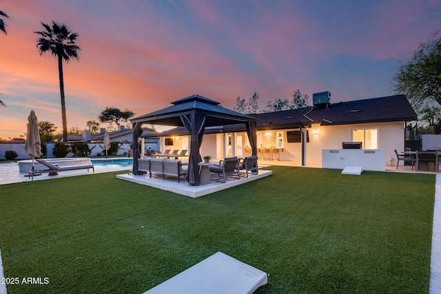 back of property at dusk with a gazebo, a fenced in pool, an outdoor living space, a patio area, and a yard