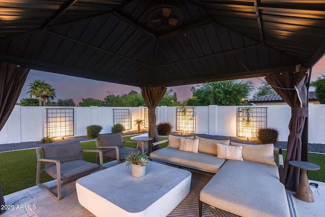 patio terrace at dusk with a gazebo, a fenced backyard, and an outdoor hangout area