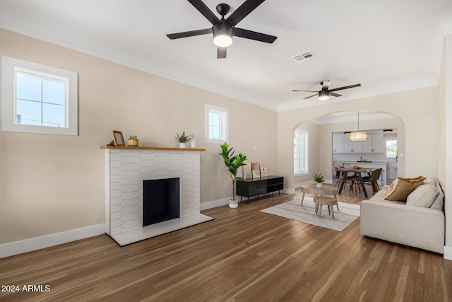 living room featuring a fireplace, hardwood / wood-style flooring, ceiling fan, and crown molding