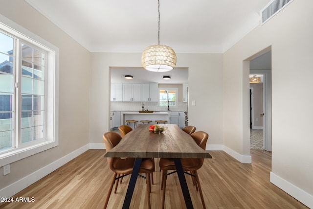 dining area featuring sink, light hardwood / wood-style floors, and ornamental molding