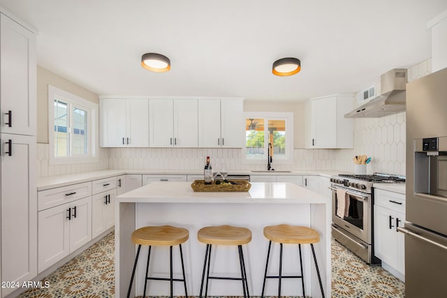 kitchen featuring white cabinets, appliances with stainless steel finishes, a kitchen breakfast bar, and a healthy amount of sunlight