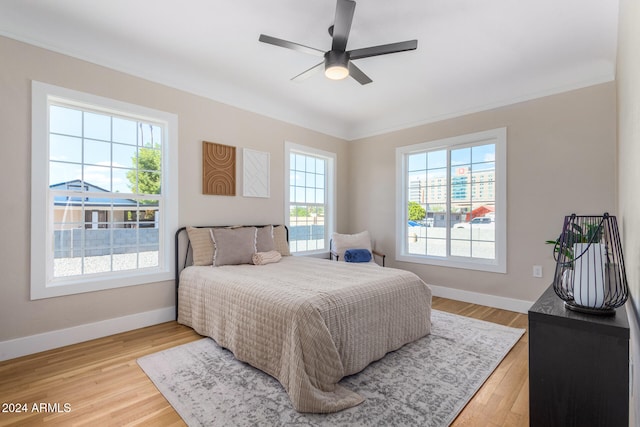 bedroom featuring multiple windows, ceiling fan, crown molding, and light hardwood / wood-style floors