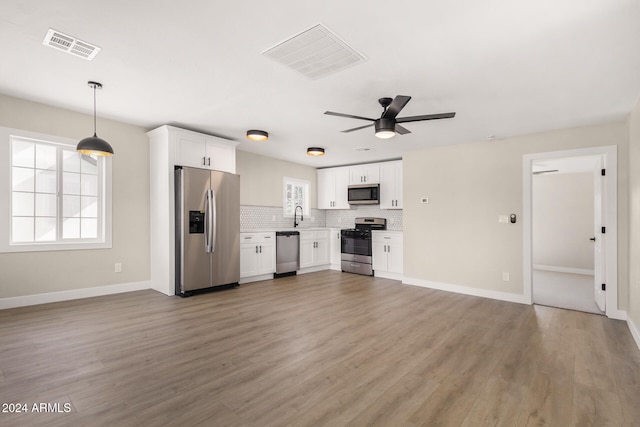 kitchen featuring hardwood / wood-style floors, stainless steel appliances, white cabinetry, and plenty of natural light