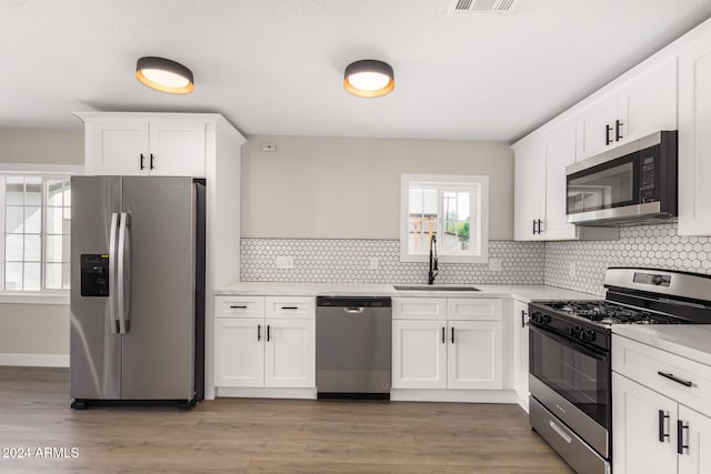 kitchen with white cabinets, light hardwood / wood-style floors, sink, and appliances with stainless steel finishes