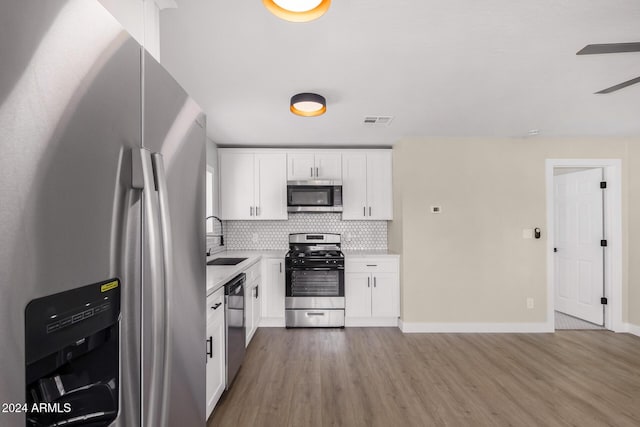1921 E Yale St, Phoenix, AZ 85006 - kitchen featuring stainless steel appliances, wood finished floors, backsplash, white cabinetry, and light countertops