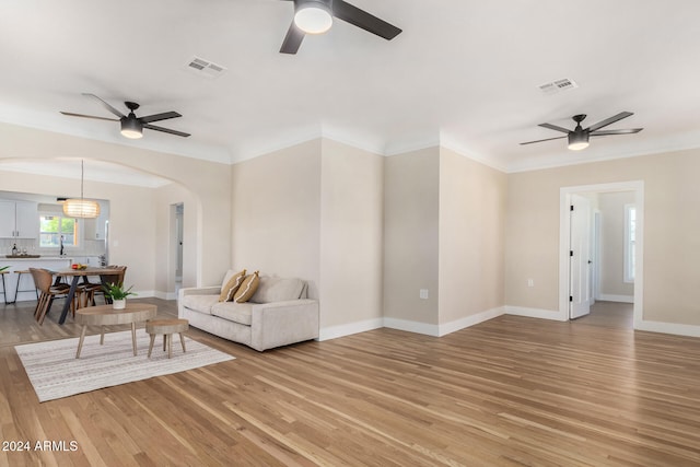 living room featuring hardwood / wood-style flooring, ceiling fan, and crown molding