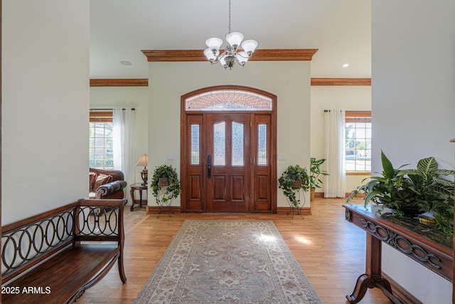 foyer featuring ornamental molding, light wood-style floors, and a healthy amount of sunlight