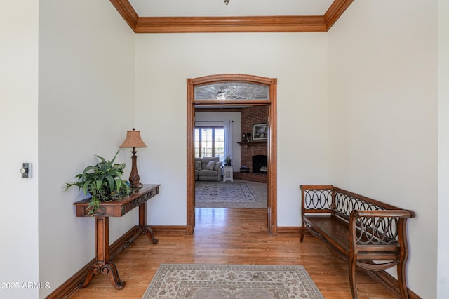 hallway with light wood finished floors, baseboards, and crown molding