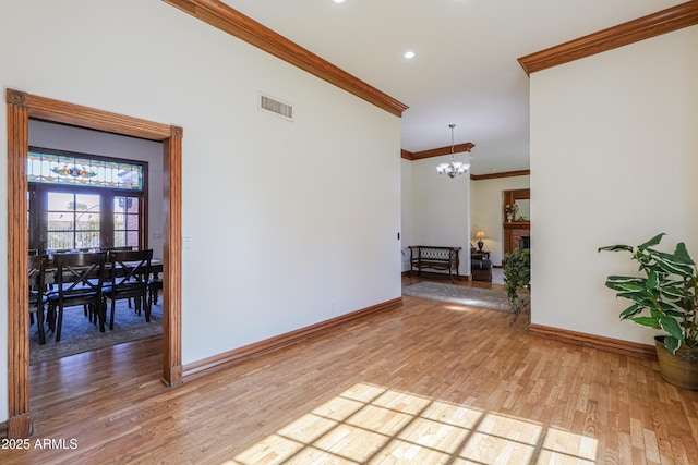 corridor featuring a notable chandelier, visible vents, baseboards, light wood-type flooring, and crown molding