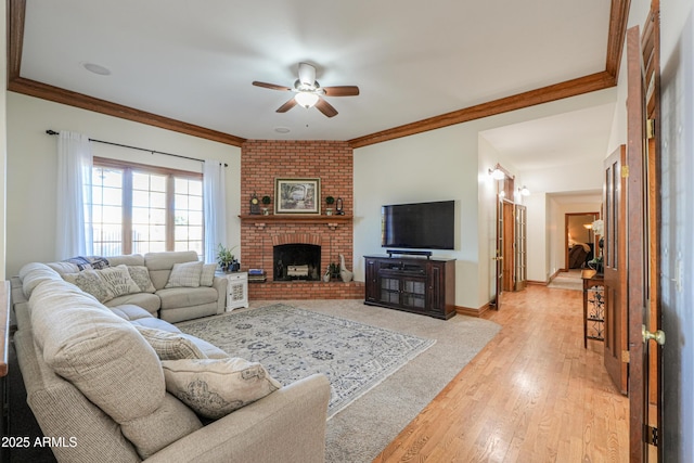 living room featuring baseboards, ceiling fan, ornamental molding, light wood-style floors, and a fireplace