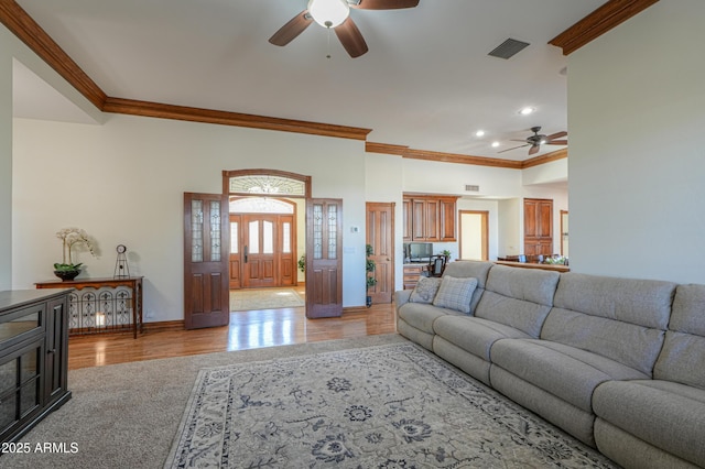 living room with a ceiling fan, baseboards, light wood-style floors, visible vents, and crown molding