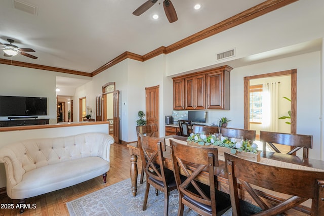 dining room with ornamental molding, a ceiling fan, visible vents, and wood finished floors