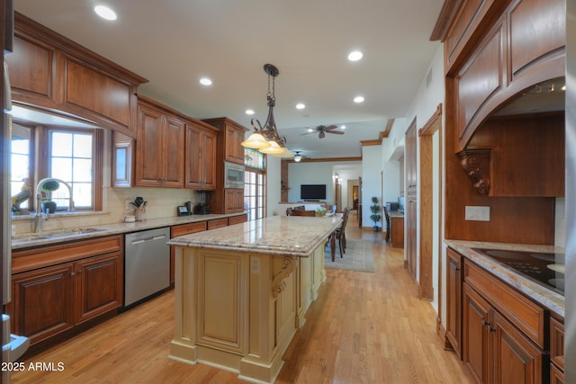 kitchen featuring light stone counters, stainless steel appliances, a sink, a kitchen island, and pendant lighting