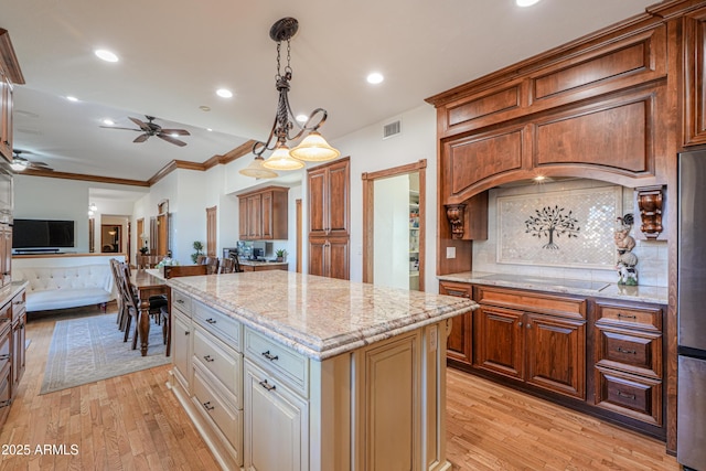 kitchen featuring black electric stovetop, light wood-style floors, visible vents, and a center island