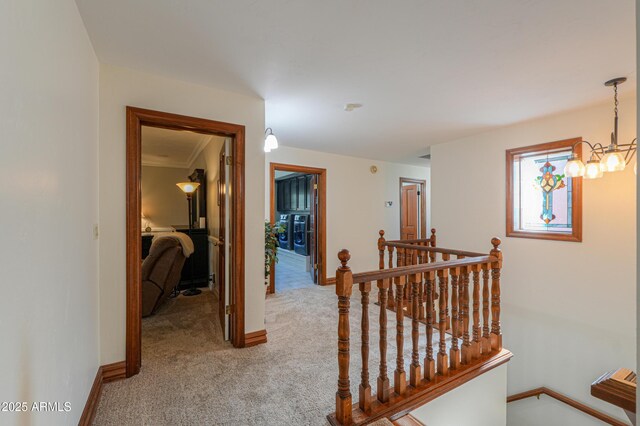 corridor featuring carpet, baseboards, a chandelier, and an upstairs landing