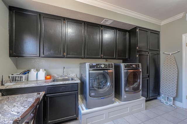 washroom featuring crown molding, washer and clothes dryer, light tile patterned floors, cabinet space, and a sink