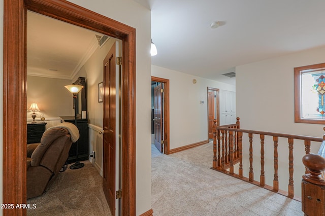 hall with light colored carpet, visible vents, baseboards, an upstairs landing, and ornamental molding