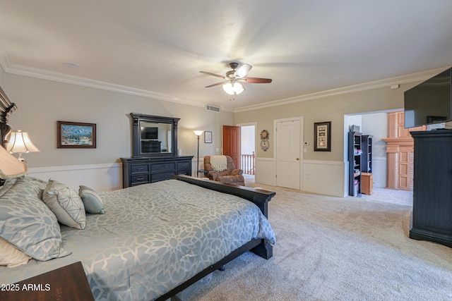 bedroom featuring visible vents, light colored carpet, crown molding, and wainscoting