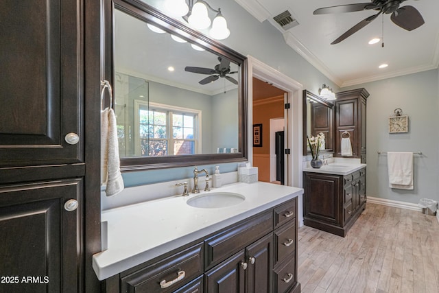 full bath featuring wood finished floors, a sink, visible vents, and crown molding