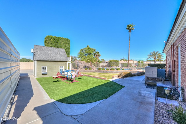 view of yard with an outbuilding, a fenced backyard, and a patio