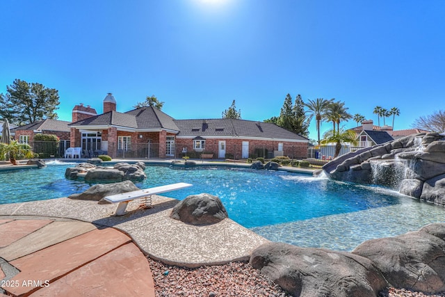 pool featuring fence, a diving board, and a water slide