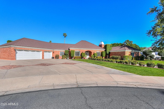 view of front of property with an attached garage, brick siding, a tiled roof, driveway, and a front lawn