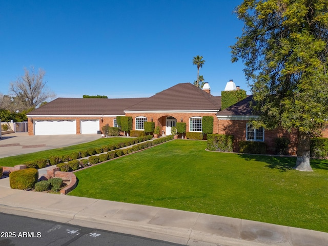 view of front facade with a front lawn, brick siding, driveway, and an attached garage