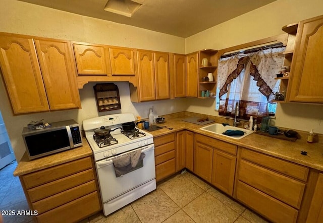 kitchen featuring white range with gas stovetop, stainless steel microwave, light countertops, open shelves, and a sink