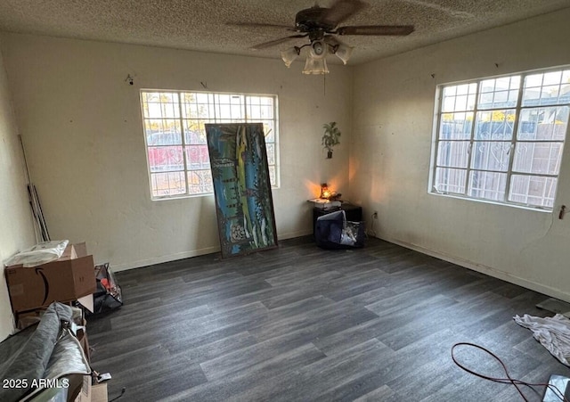 interior space featuring a ceiling fan, a textured ceiling, baseboards, and wood finished floors