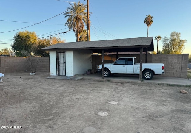 view of parking with a carport and fence