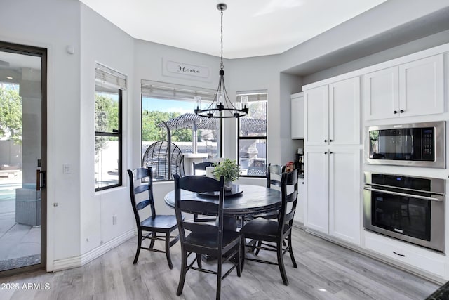 dining room featuring light wood-style flooring, baseboards, and an inviting chandelier