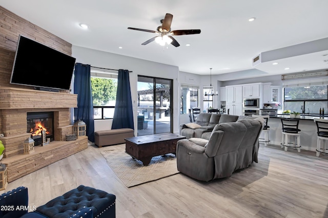 living area featuring a stone fireplace, light wood-style flooring, and recessed lighting