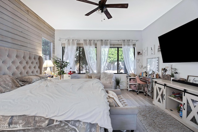 bedroom featuring ceiling fan, wood walls, and wood finished floors