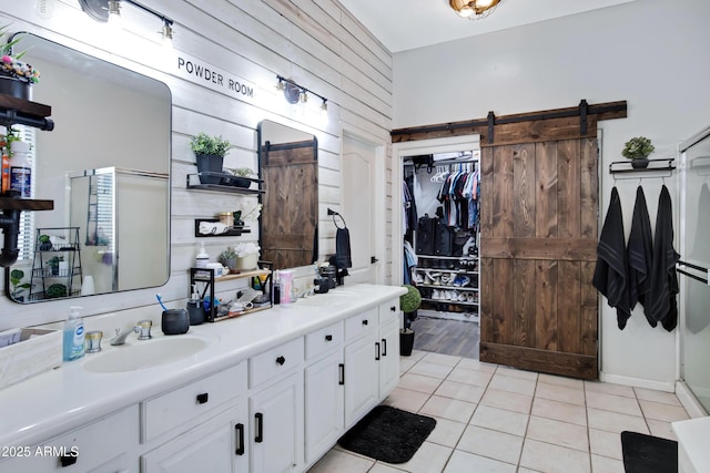 bathroom featuring tile patterned flooring, a sink, a spacious closet, and double vanity