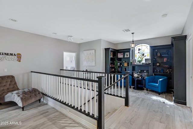 interior space with an inviting chandelier, visible vents, an upstairs landing, and wood finished floors