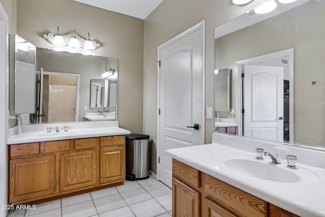 bathroom with tile patterned flooring, visible vents, two vanities, and a sink