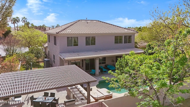 back of house featuring a patio, a tiled roof, fence, a swimming pool, and stucco siding