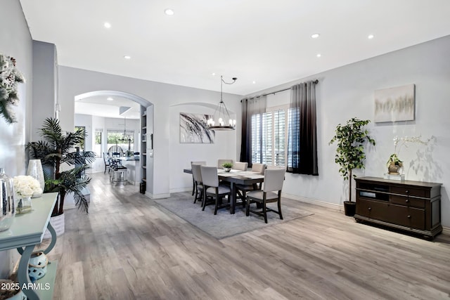 dining space featuring a healthy amount of sunlight, light wood-type flooring, and a notable chandelier