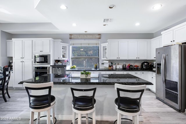 kitchen with appliances with stainless steel finishes, white cabinetry, and light wood-style floors