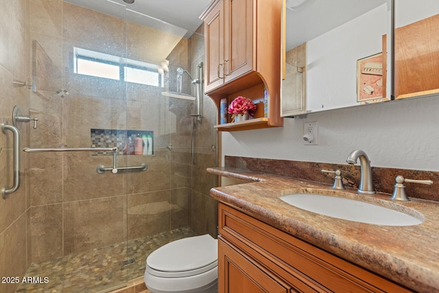 bathroom with toilet, a shower stall, and vanity