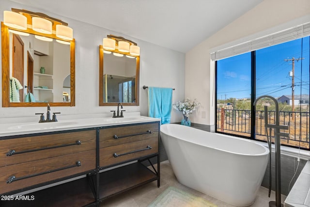 bathroom with vaulted ceiling, a freestanding tub, a sink, and double vanity