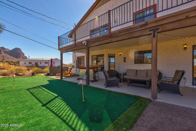 exterior space featuring a hot tub, a patio, an outdoor hangout area, a mountain view, and stucco siding