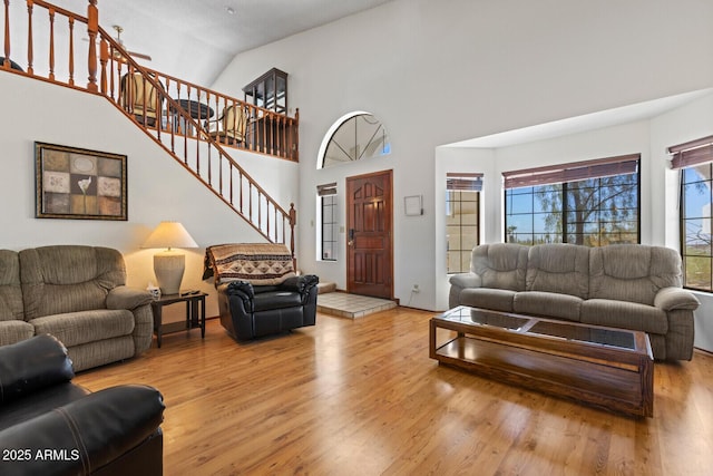 living room with high vaulted ceiling, wood finished floors, and stairs