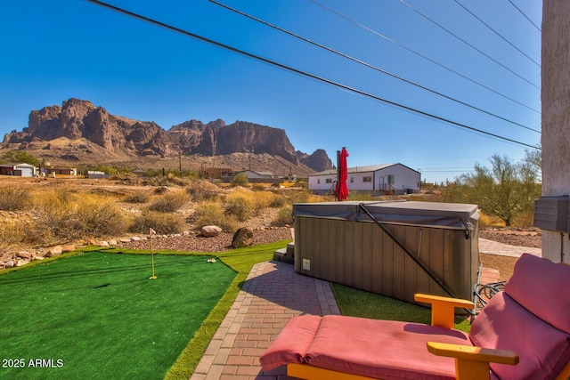 exterior space with a patio area, a mountain view, and a hot tub